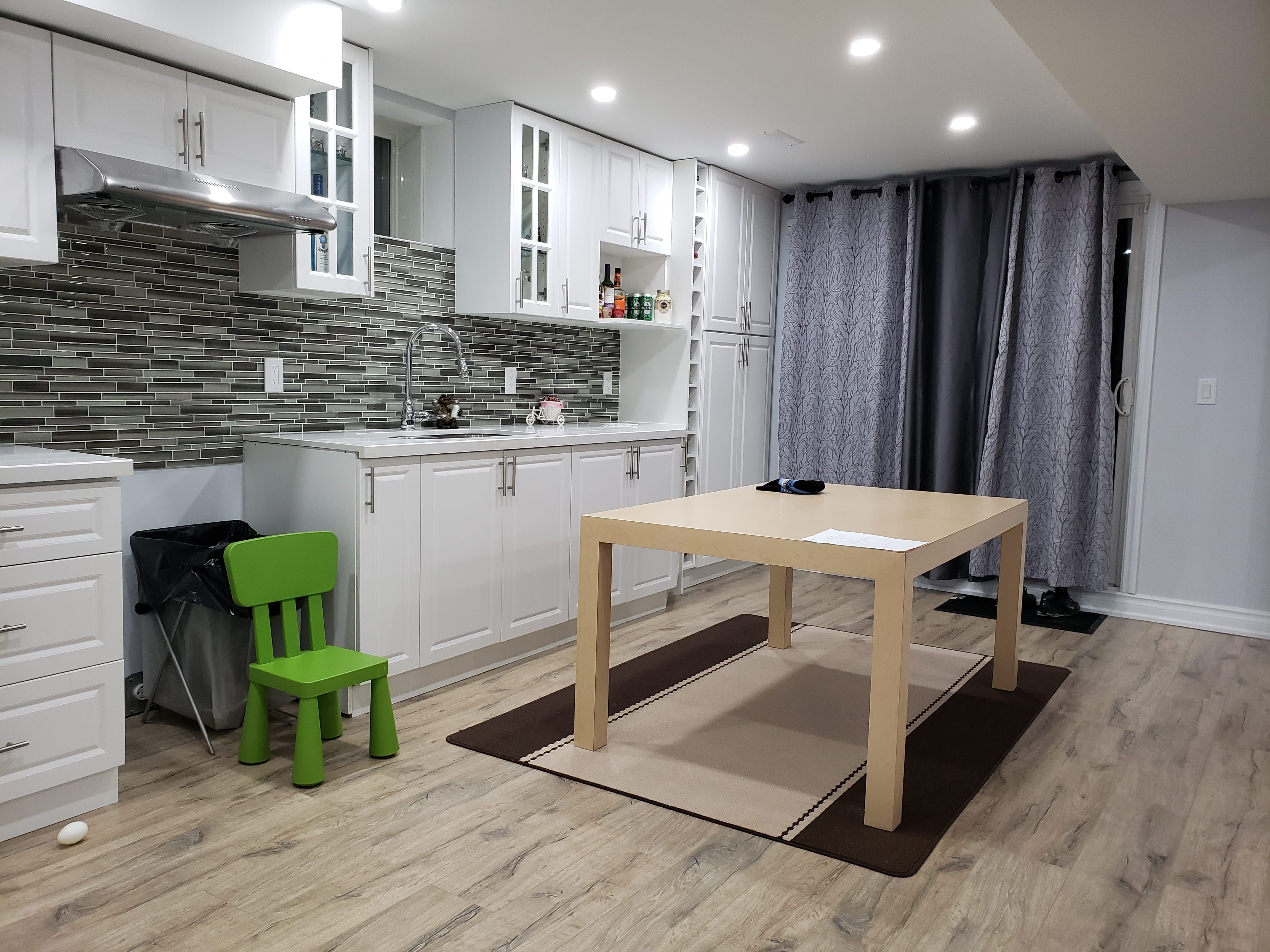 This modern basement kitchen renovation in Newmarket, Toronto features custom white cabinetry, a contemporary mosaic tile backsplash, and upgraded recessed pot lighting to create a bright and functional space. The layout includes ample storage, extended countertop workspace, and durable wood-look flooring designed for long-term basement use. Neutral tones and clean finishes enhance the sense of openness, while the integrated dining area makes the space ideal for family living or rental potential. Completed by an experienced Toronto renovation company, this basement upgrade focuses on practicality, modern aesthetics, and efficient use of space.