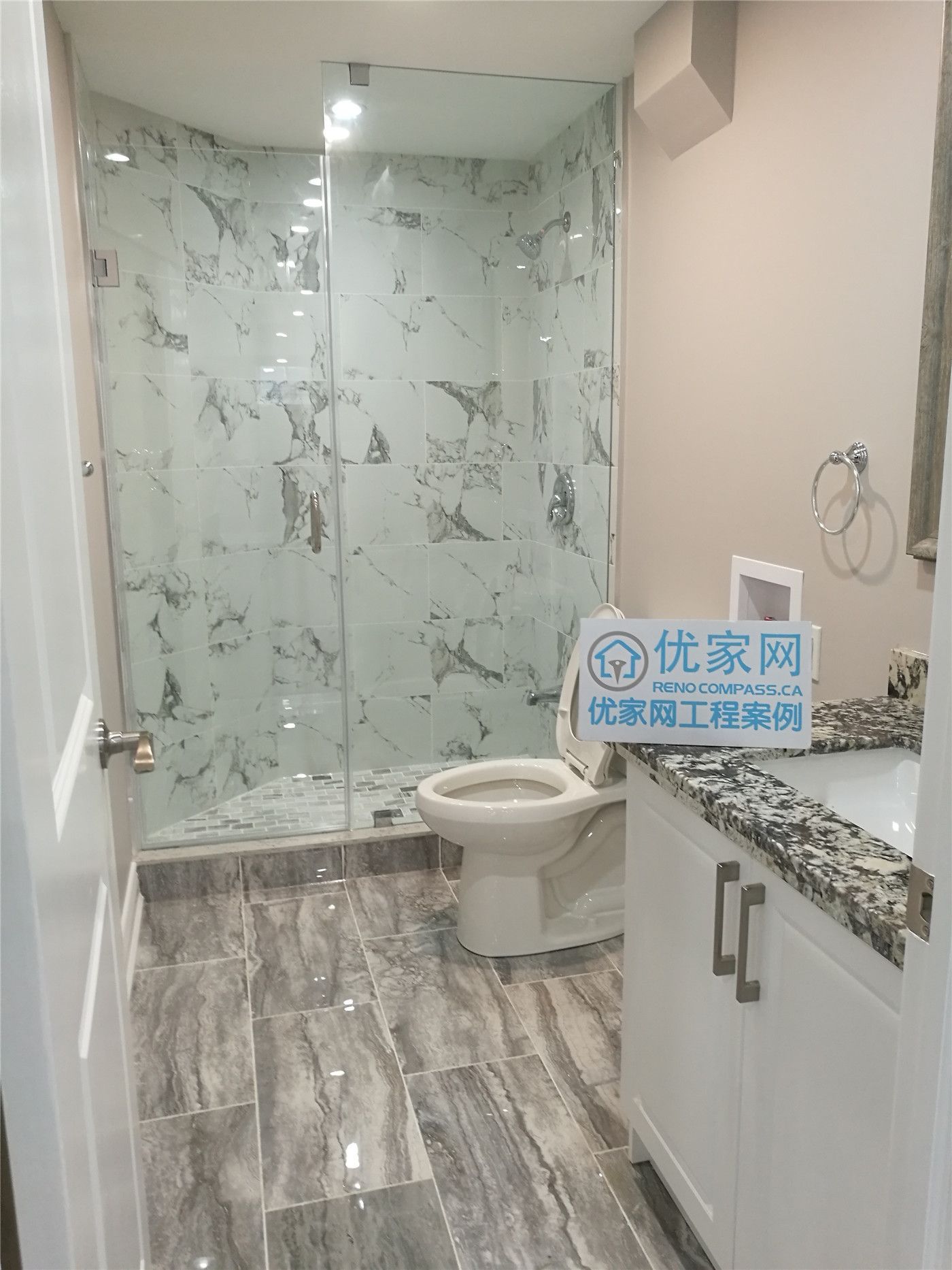 This image features a newly completed Richmond Hill basement bathroom renovation, highlighting a modern glass-enclosed shower with marble-look wall tiles, upgraded floor tiling, and a sleek vanity with stone countertop. The bathroom design maximizes space and functionality while maintaining a clean, contemporary aesthetic. This basement bathroom remodel was completed by an experienced Toronto renovation company, providing high-quality renovation solutions for Richmond Hill homeowners.