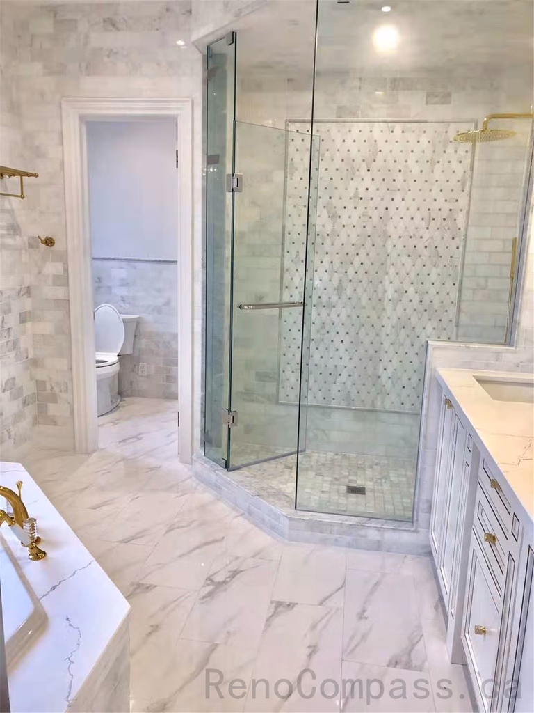 This North York luxury bathroom renovation features a spacious glass walk-in shower with marble-look tiles and mosaic accent wall, paired with a custom vanity, quartz countertop, and elegant gold fixtures. The bright open layout enhances comfort, functionality, and a refined modern aesthetic. Completed by a professional Toronto renovation company specializing in high-end residential bathroom renovations.