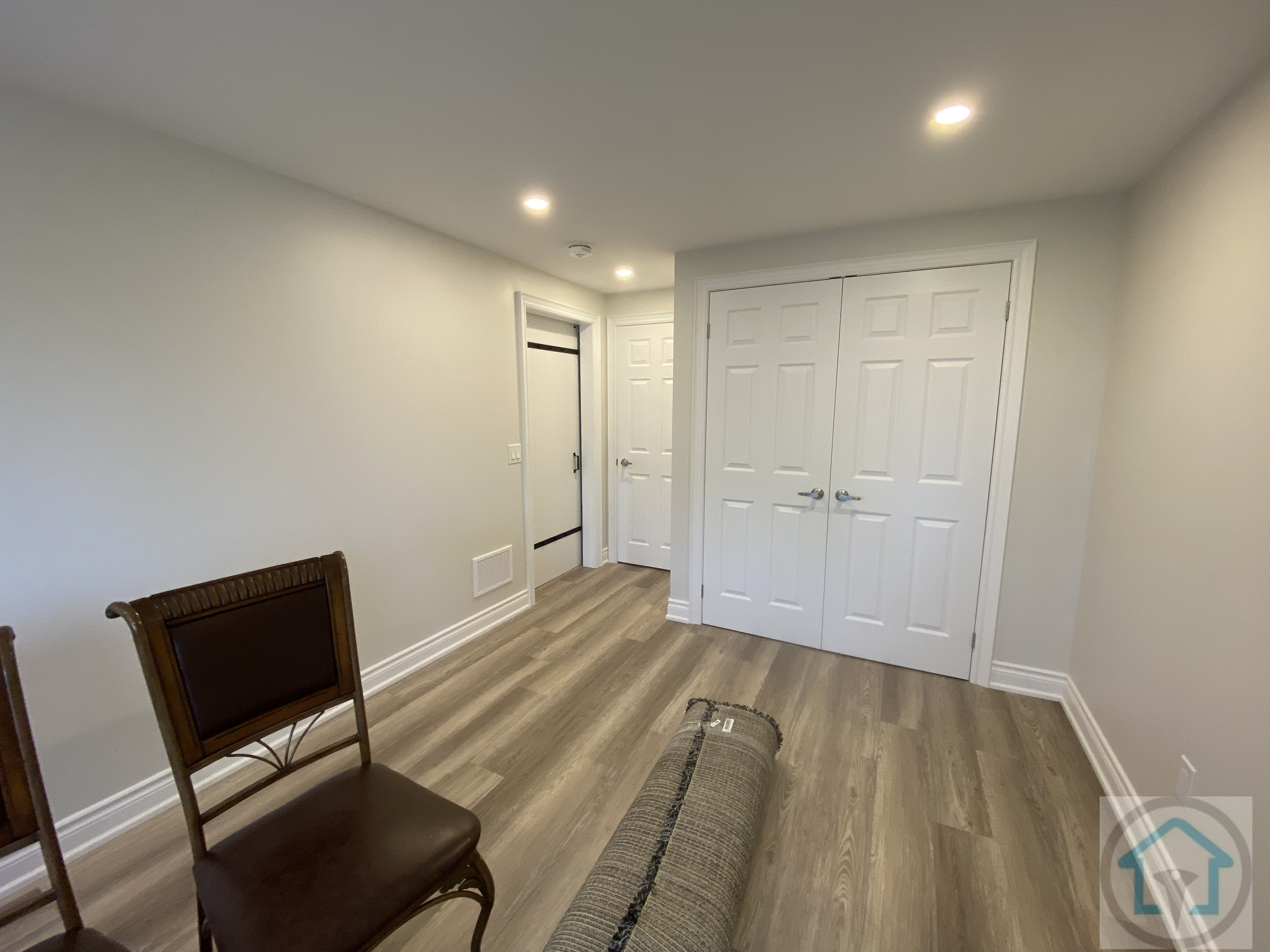 This finished room in a Newmarket basement renovation features upgraded flooring, recessed ceiling lighting, and built-in storage closets. The clean finishes and efficient layout create a flexible space suitable for a home office, hobby room, or secondary living area within the basement.