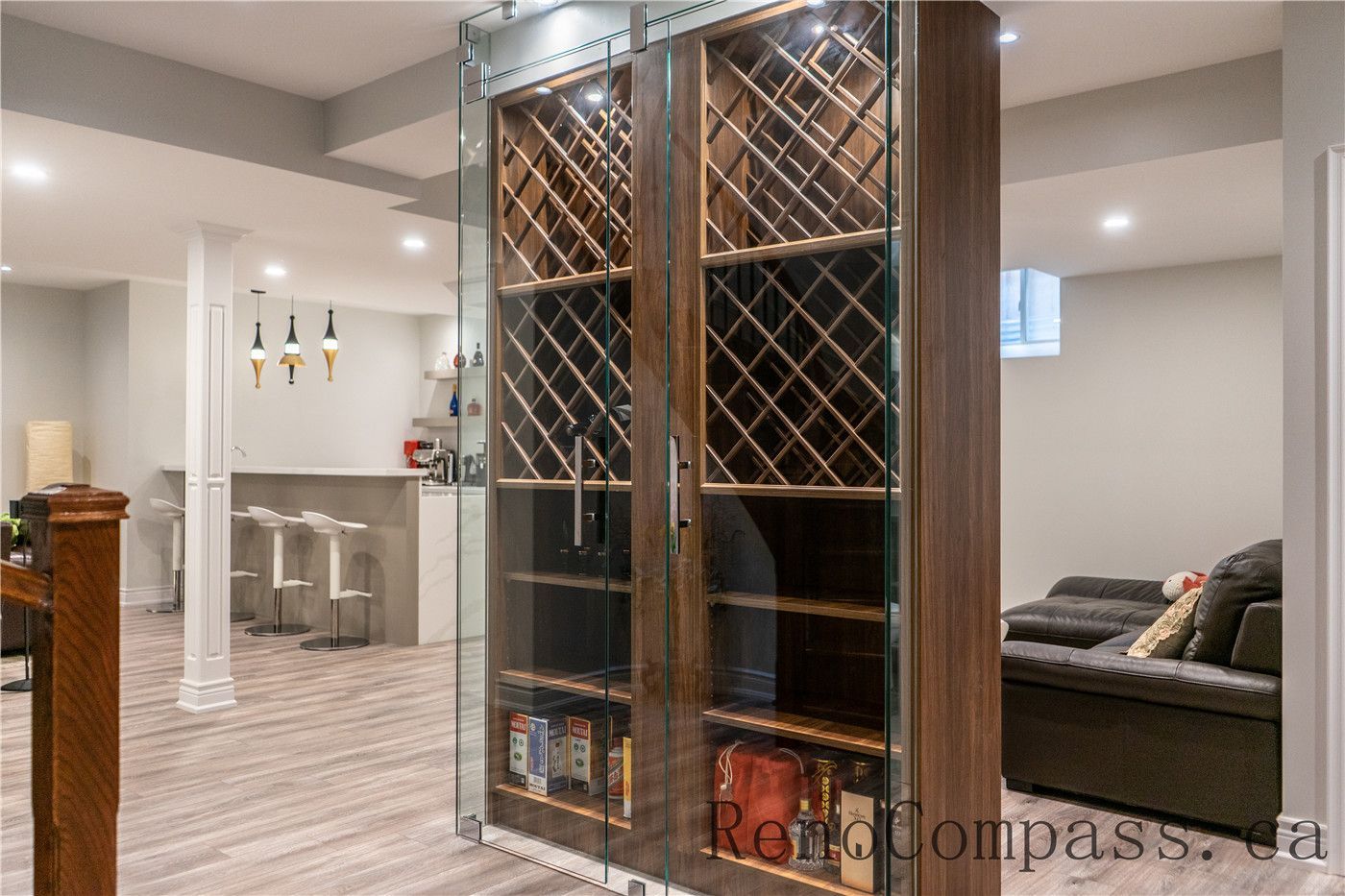 This Richmond Hill basement renovation features a custom glass wine cellar with built-in wood storage, modern lighting, and a nearby bar and entertainment area. The sophisticated design enhances both storage and lifestyle experience, showcasing the craftsmanship of a trusted Toronto renovation company specializing in full house interior and basement renovations.