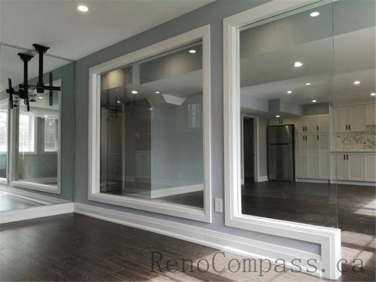 Contemporary basement renovation with a glass partition wall, maximizing natural light and creating an open, seamless flow between spaces. A refined Aurora project designed and built by Reno Compass.