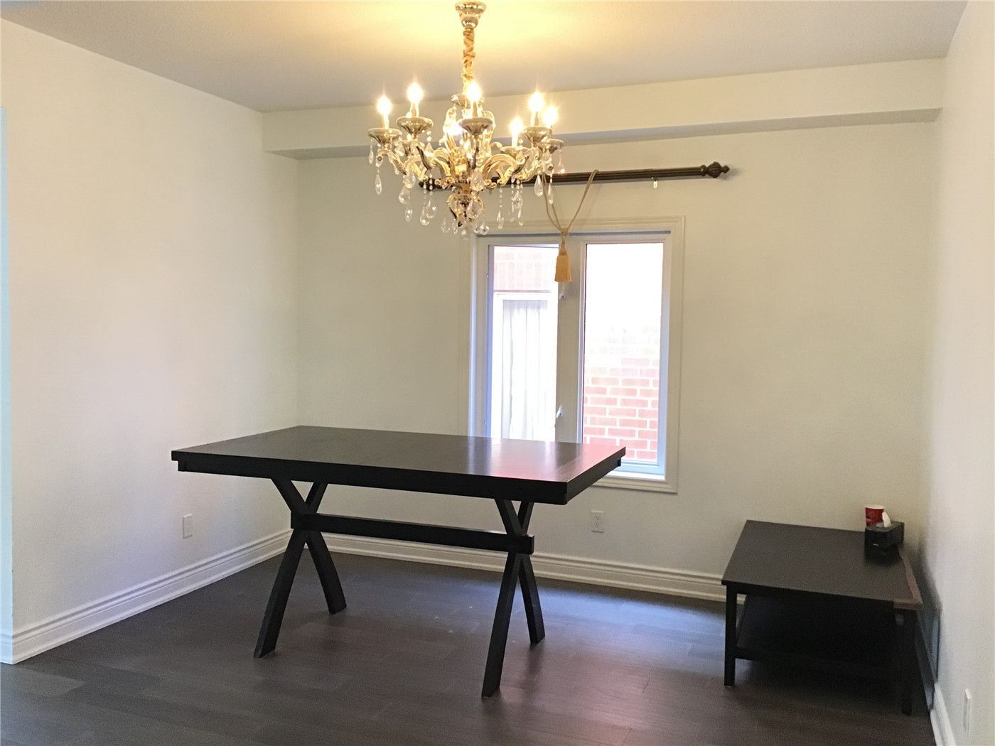This Woodbridge interior renovation features a bright and inviting dining area with elegant chandelier lighting, wide plank hardwood flooring, and a clean minimalist layout. The space is designed to enhance natural light and create a warm, functional environment for everyday dining and gatherings.