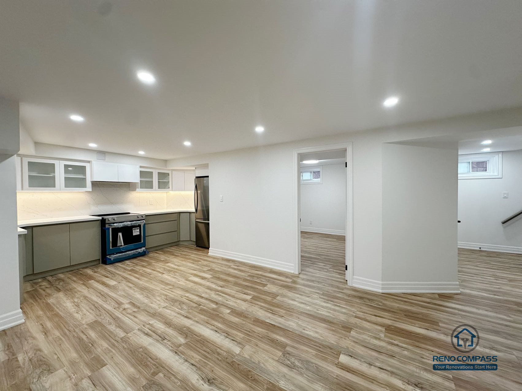 This image presents a completed open-concept basement renovation in Pickering, highlighting the overall spatial layout and flow between the kitchen, living area, and adjacent rooms. The design emphasizes flexibility and usability, with consistent flooring, recessed ceiling lighting, and clear circulation throughout the space. The kitchen is seamlessly integrated into the open layout, allowing the basement to function as an extension of the main living area. Neutral finishes and balanced proportions contribute to a bright, cohesive environment suitable for everyday living, entertainment, or multi-purpose use.
Location: Pickering · Toronto Contractor: Reno Compass