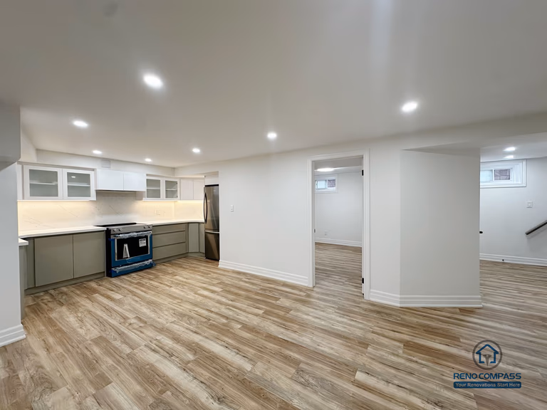 This image presents a completed open-concept basement renovation in Pickering, highlighting the overall spatial layout and flow between the kitchen, living area, and adjacent rooms. The design emphasizes flexibility and usability, with consistent flooring, recessed ceiling lighting, and clear circulation throughout the space. The kitchen is seamlessly integrated into the open layout, allowing the basement to function as an extension of the main living area. Neutral finishes and balanced proportions contribute to a bright, cohesive environment suitable for everyday living, entertainment, or multi-purpose use.
Location: Pickering · Toronto Contractor: Reno Compass