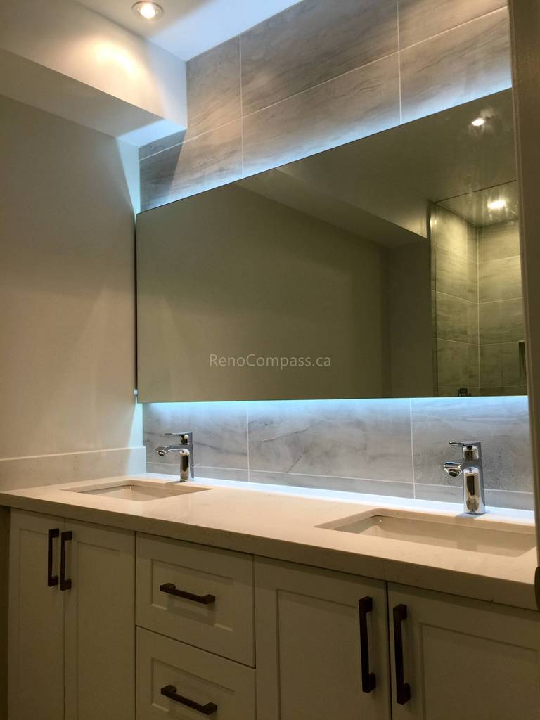 A modern bathroom interior renovation in Toronto featuring a custom double-sink vanity, integrated LED mirror lighting, and sleek contemporary fixtures. The design focuses on functionality, clean detailing, and soft ambient lighting, highlighting professional Toronto interior renovation and interior design craftsmanship