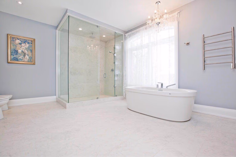 Luxury master bathroom completed as part of a Toronto design build and whole house renovation Toronto project, featuring a freestanding bathtub, frameless glass shower enclosure, elegant chandelier lighting, and spacious layout. Designed and built by a professional Toronto Renovation Company, this bathroom combines modern comfort, refined finishes, and functional luxury typical of high-end custom homes in Toronto.