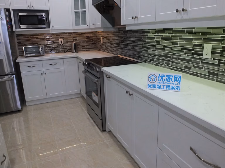 This Vaughan kitchen renovation showcases a bright modern layout with white shaker cabinets, quartz countertops, stainless steel appliances, and a stylish glass mosaic backsplash enhanced with LED lighting. The long galley-style layout maximizes workspace and storage while creating a clean contemporary design. Completed by a professional Toronto renovation company, the project delivers both functionality and elegant kitchen aesthetics.