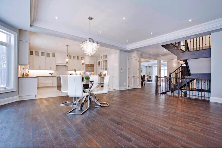 Bright open-concept kitchen and dining area completed as part of a Toronto design build custom build project, featuring a spacious layout with large windows, hardwood flooring, and a modern kitchen island. This whole house renovation Toronto project highlights the seamless connection between cooking, dining, and living spaces, creating a functional and elegant interior commonly found in luxury custom homes across Toronto.