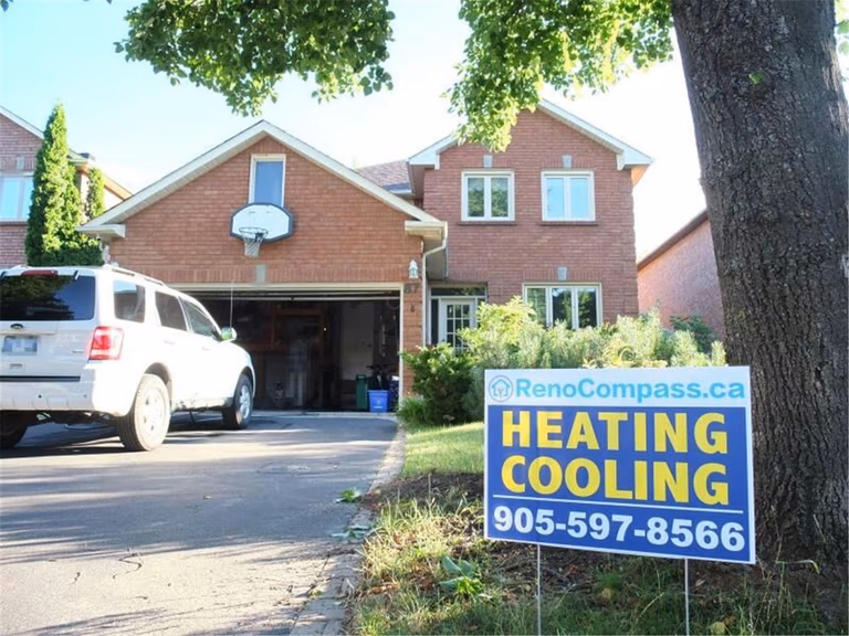 Professional outdoor air conditioner condenser installation by Reno Compass in Toronto. This energy-efficient HVAC unit is securely mounted on a raised stand with proper drainage and ventilation clearance, ensuring optimal cooling performance, durability, and safe operation for residential homes. Installed by licensed technicians for long-term reliability and comfort.