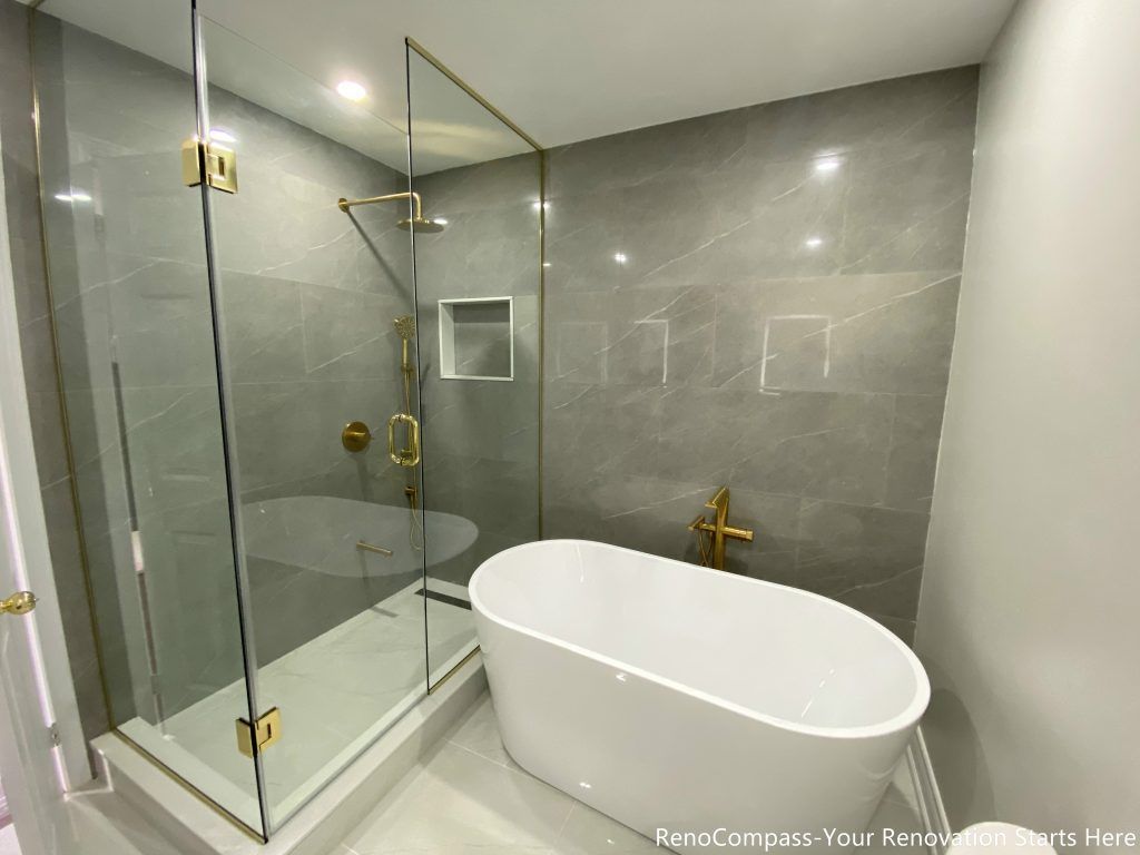 This Oakville master bathroom renovation features a sleek freestanding bathtub paired with premium gold floor-mounted fixtures and large-format marble-look wall tiles. The clean layout integrates a glass-enclosed shower and modern toilet placement, creating a functional yet luxurious spa-style bathroom environment. Completed by a professional Toronto renovation company, this upgrade enhances comfort, improves space efficiency, and delivers a timeless modern design that increases both daily living quality and overall property value.