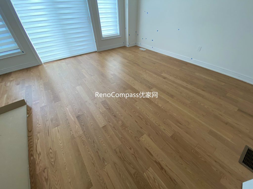 Spacious living area renovation in Richmond Hill highlighting warm wood laminate flooring, crisp wall finishes, and refined trim details. Reno Compass designed this renovation for style, comfort, and durability.