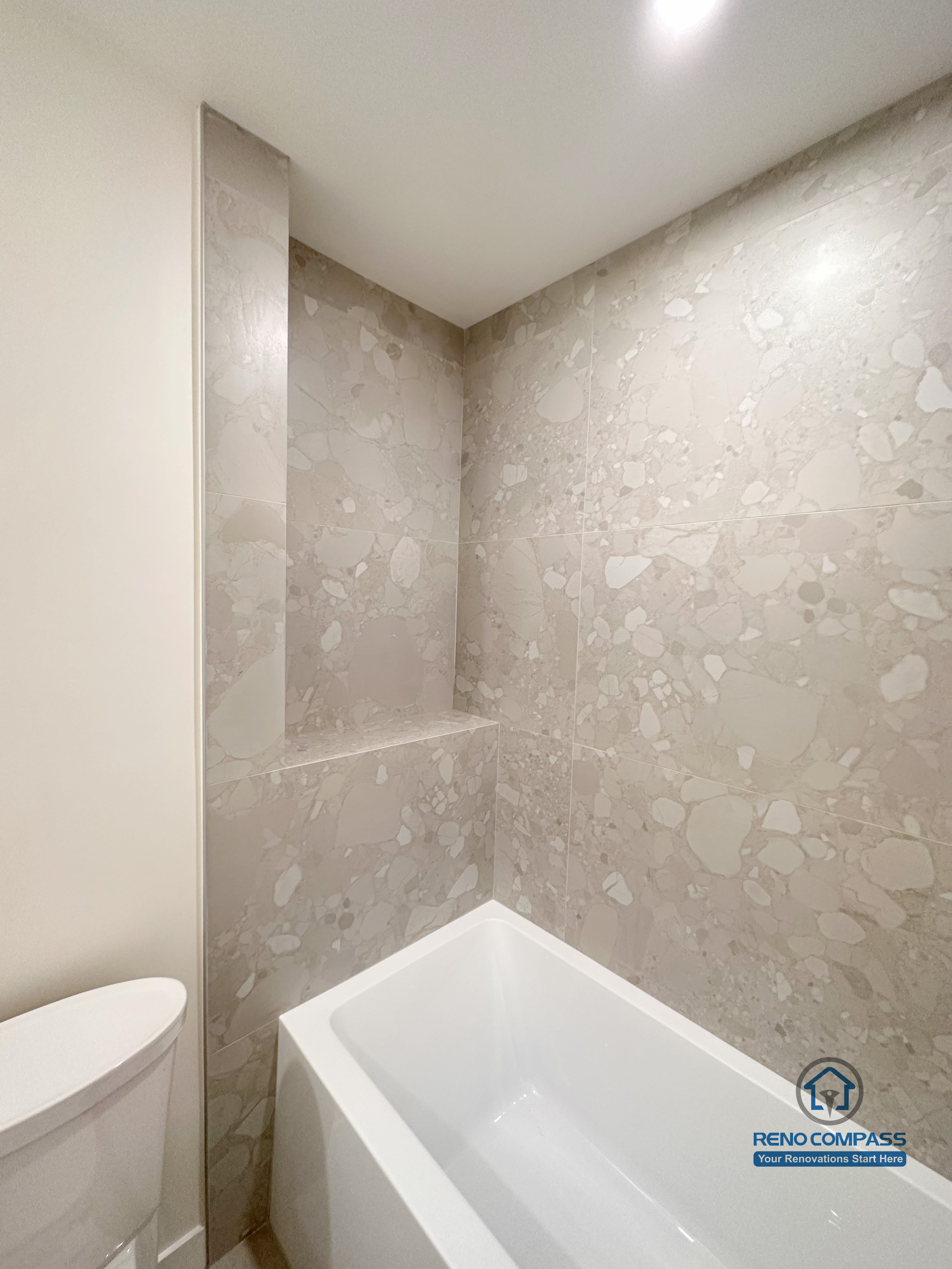 Bathroom renovation detail in Markham featuring a bathtub with full-height tile surround and a built-in shower niche. The large-format stone-look tiles provide a clean, durable, and low-maintenance finish while adding subtle texture to the modern bathroom design.
