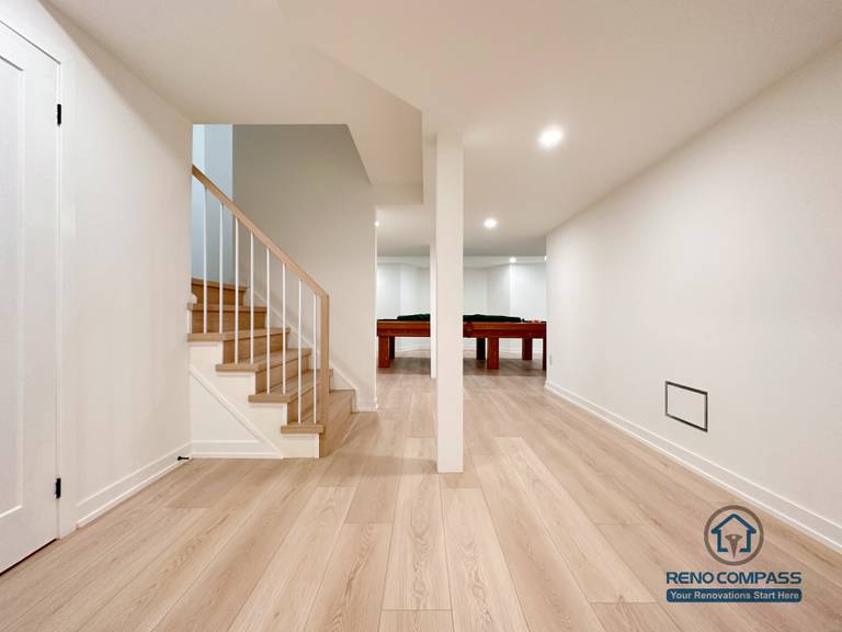 This Markham basement renovation features a clean, open-concept layout with wide-plank flooring, recessed ceiling lights, and a solid wood staircase that creates a seamless connection between levels. Structural columns are carefully integrated to maintain openness while ensuring long-term stability. Designed and completed by a professional Toronto renovation company, this basement space is ideal for a family living area, entertainment zone, or flexible multi-purpose use.
