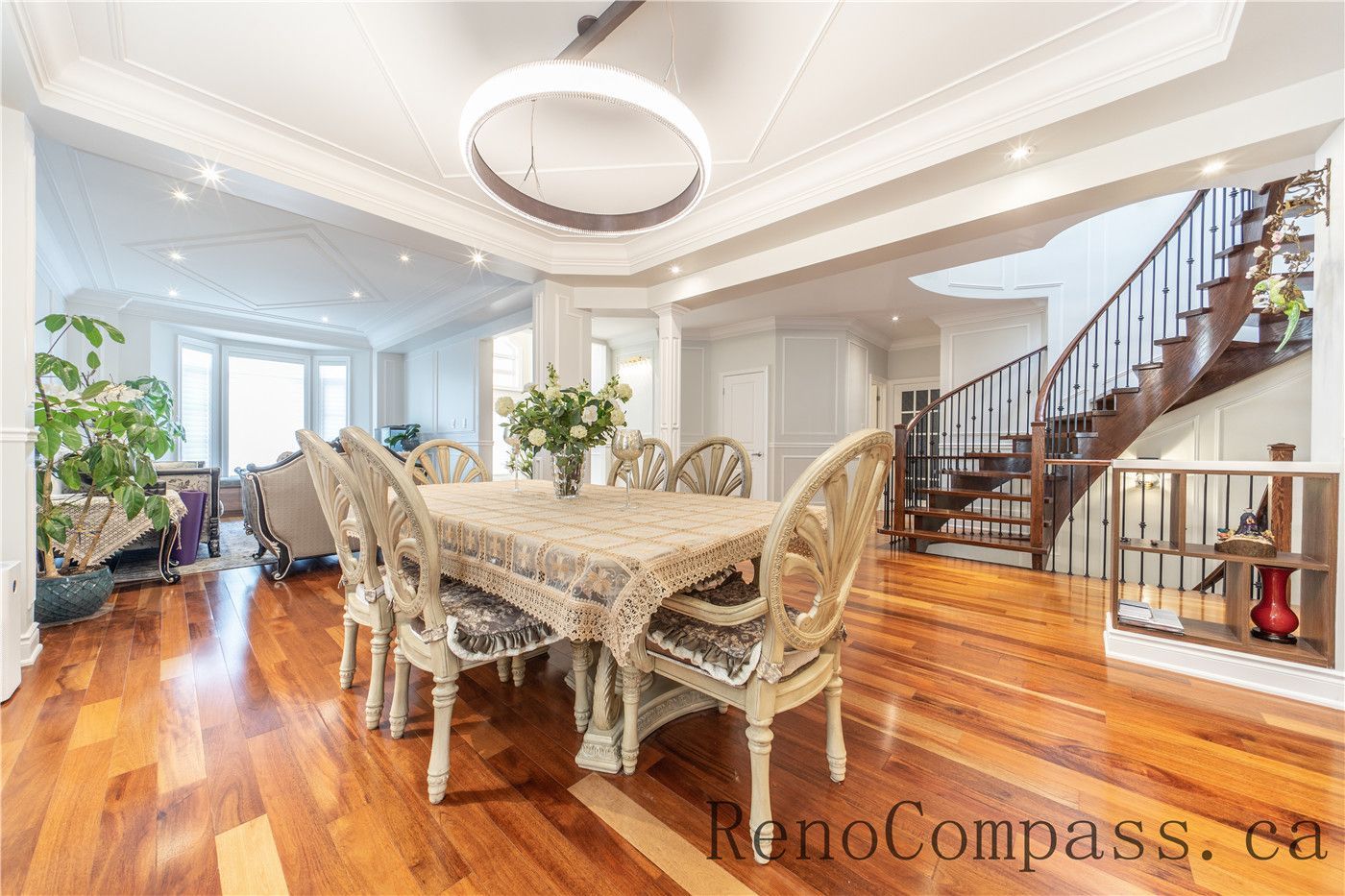 This Richmond Hill entire house interior renovation highlights an elegant open-concept dining and living area featuring rich hardwood flooring, custom ceiling detailing, and decorative columns. Large windows and a bright foyer connection enhance natural light and spatial flow throughout the home. The refined layout and timeless finishes create a warm, luxurious atmosphere, professionally completed by a leading Toronto renovation company focused on quality craftsmanship and modern functionality.