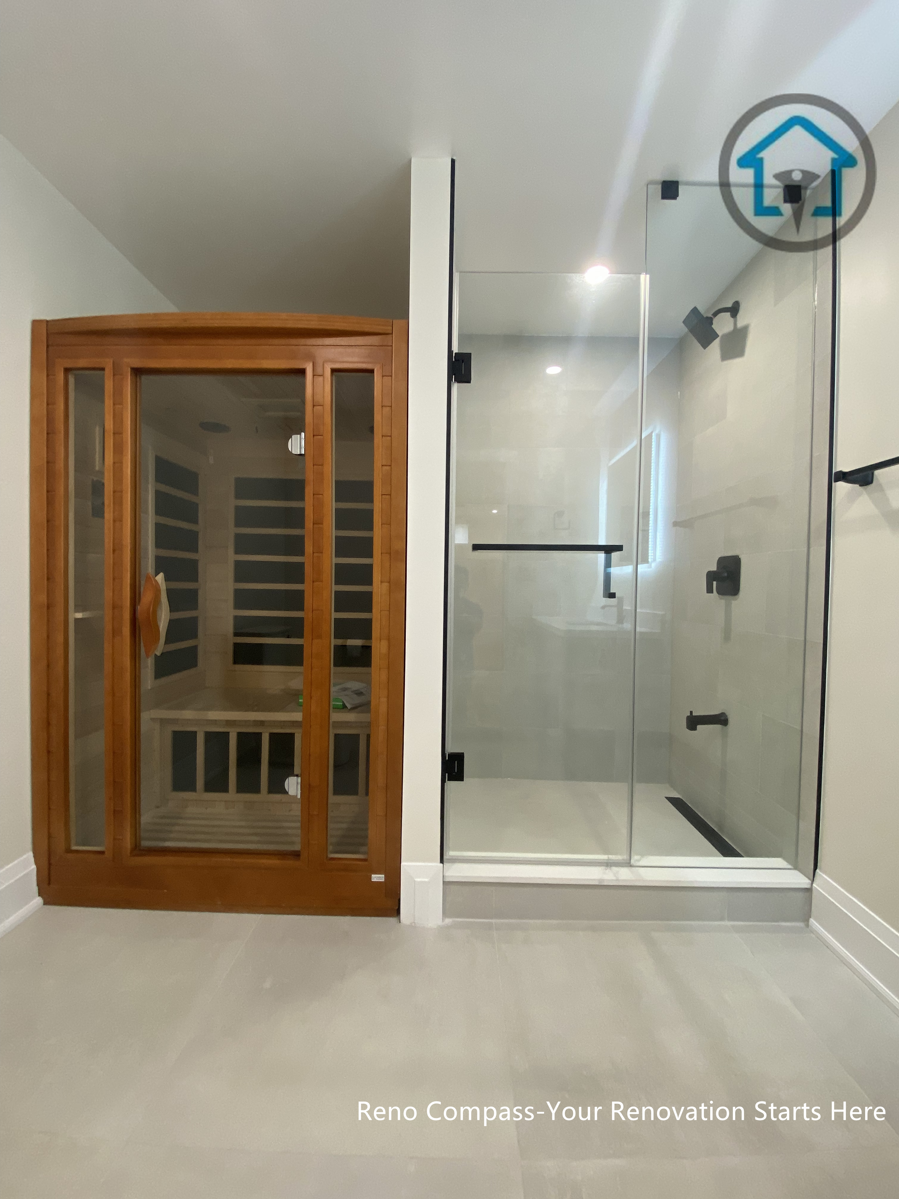 This image showcases a luxury bathroom renovation in Richmond Hill, featuring a frameless glass shower paired with a custom-built sauna. Clean tile finishes, minimalist black fixtures, and a clear spatial separation create a spa-inspired environment designed for relaxation and daily comfort. Designed and completed by Reno Compass, this bathroom renovation reflects a refined approach to wellness-focused interior design for homes in Richmond Hill.