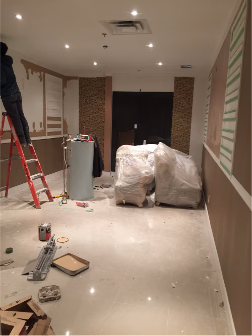 该图片展示一万尺大型娱乐中心在翻新施工阶段的室内走廊区域，由专业多伦多装修公司负责整体商业空间升级工程。现场正在进行墙面翻新、灯光系统安装及空间细节优化施工，重点提升公共区域的视觉效果与客户体验。项目通过现代化照明设计、墙面装饰升级与功能动线优化，打造更具质感与商业氛围的娱乐休闲环境，为整体娱乐中心空间呈现奠定高品质基础。