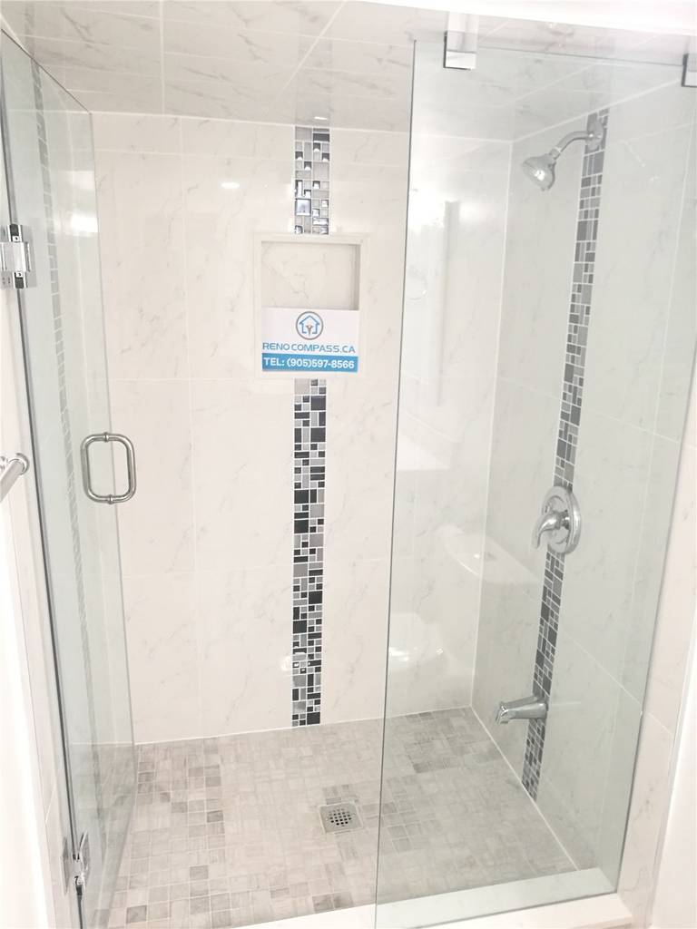 Bathroom renovation project in Pickering featuring a modern white vanity with quartz countertop, undermount sink, large mirror, and a frameless glass shower enclosure. The neutral tile flooring and clean layout enhance brightness and functionality, completed by a professional Toronto renovation company.