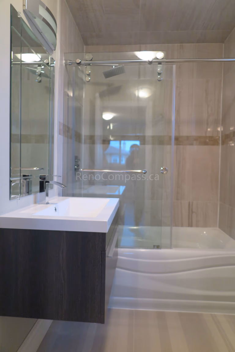 This Markham bathroom renovation features a modern glass-enclosed shower, custom floating vanity with quartz countertop, and elegant large-format wall tiles. The space is designed with clean lines, durable finishes, and contemporary fixtures to create a bright and functional bathroom layout. Completed by Reno Compass, a professional renovation contractor specializing in bathroom renovations and full interior remodeling across Markham and the Greater Toronto Area.