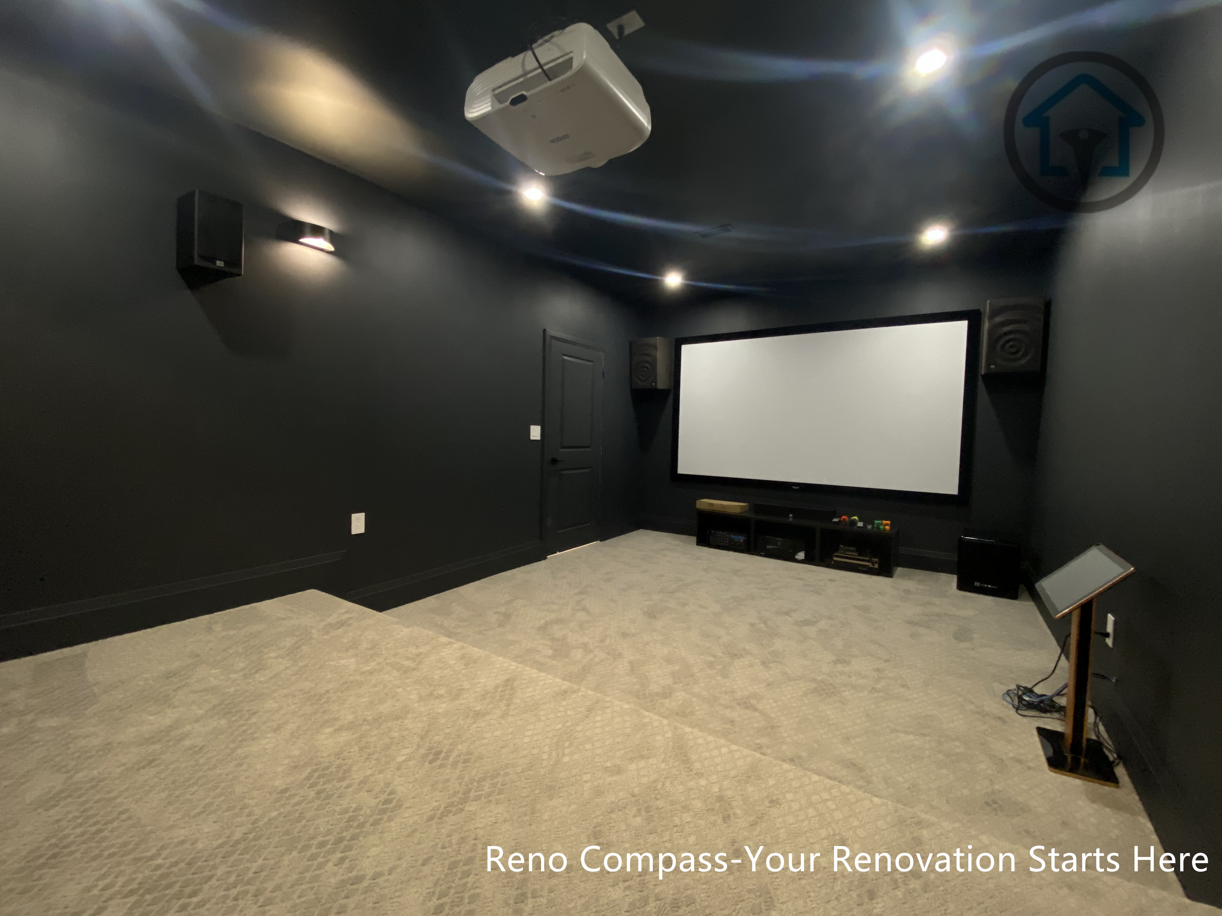 This image features a custom basement home theater renovation in Richmond Hill, designed with dark wall finishes, wall-mounted ambient lighting, and a raised platform for optimal viewing experience. The enclosed layout enhances sound control and visual focus, creating a private cinematic environment within the home. Completed by Reno Compass, this home theater renovation demonstrates thoughtful space planning and lighting design tailored for immersive entertainment in a modern basement setting.
