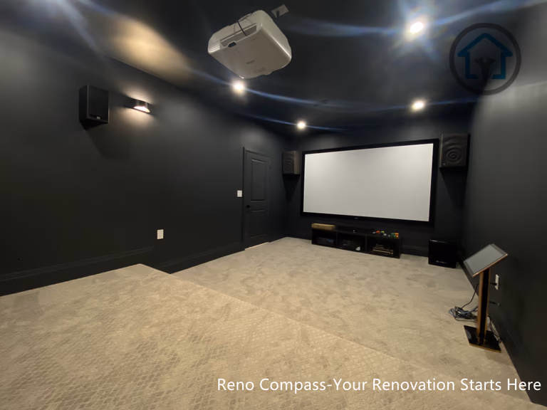 This image features a custom basement home theater renovation in Richmond Hill, designed with dark wall finishes, wall-mounted ambient lighting, and a raised platform for optimal viewing experience. The enclosed layout enhances sound control and visual focus, creating a private cinematic environment within the home. Completed by Reno Compass, this home theater renovation demonstrates thoughtful space planning and lighting design tailored for immersive entertainment in a modern basement setting.