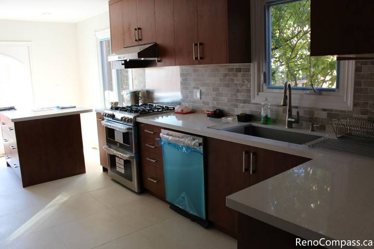 This modern kitchen is part of a full house renovation project in Mississauga completed by a professional Toronto renovation team. The space features rich wood cabinetry, quartz countertops, a contemporary backsplash, and stainless steel appliances, creating a warm yet modern cooking environment. The renovation focused on improving functionality, storage efficiency, and overall home value while delivering a clean and timeless kitchen design suitable for everyday family living.