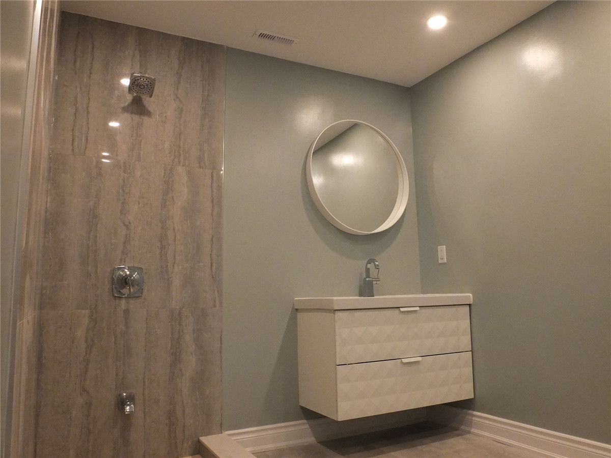 This image highlights a modern bathroom vanity renovation as part of a Mississauga interior renovation project. The design features a floating vanity with integrated drawers, a sleek single-handle faucet, and a round wall-mounted mirror that enhances visual balance. Soft neutral wall tones and minimalist finishes create a clean, contemporary look while maintaining functionality. Completed by a professional Toronto renovation company, this bathroom upgrade improves storage efficiency, space optimization, and overall interior aesthetics for Mississauga homes.