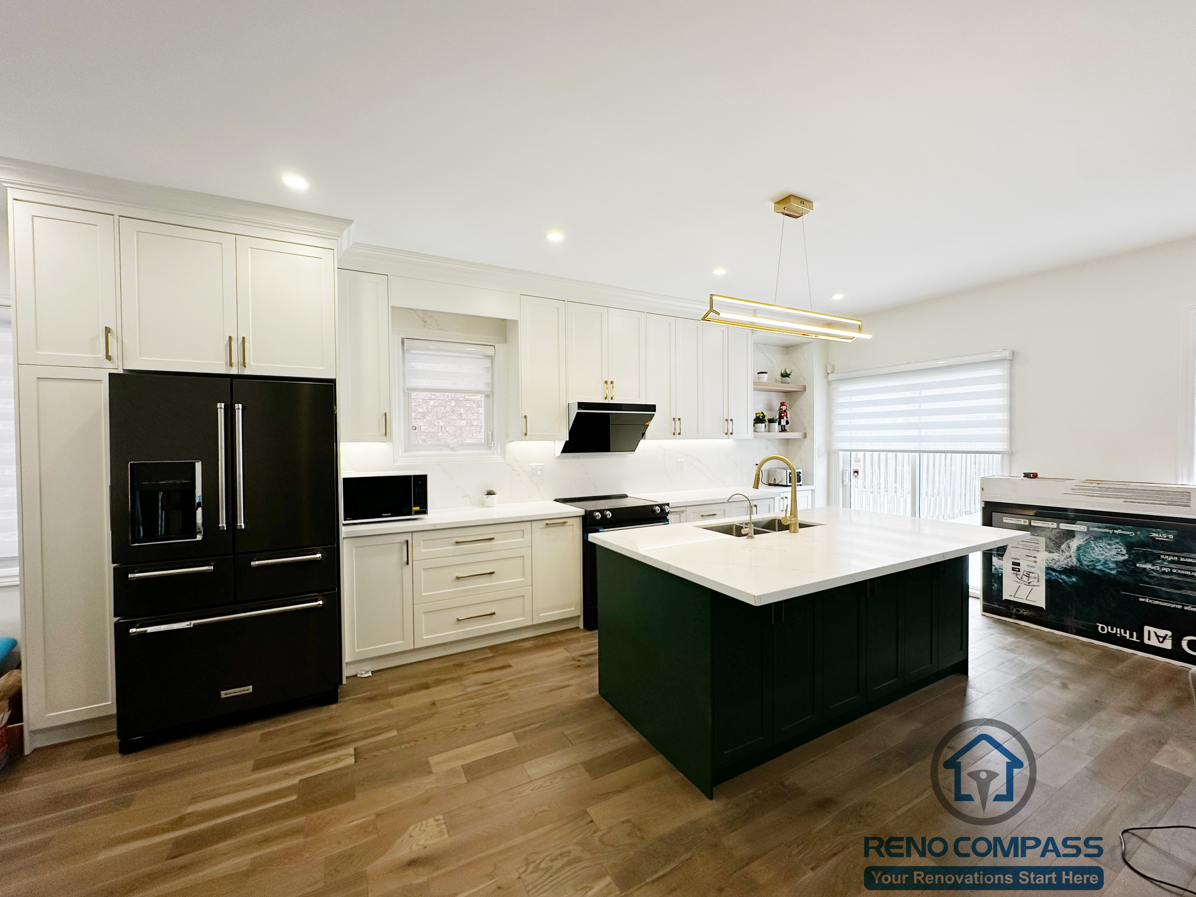 Interior renovation in Markham showcasing a modern kitchen with custom white cabinetry, a contrasting dark green island, quartz countertops, and integrated lighting. The open layout enhances functionality, flow, and everyday family use.