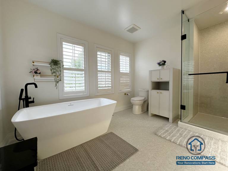 This Markham bathroom renovation showcases a freestanding bathtub set against large windows with plantation shutters. The airy layout, soft neutral finishes, and matte black fixtures create a balanced, spa-like environment that emphasizes natural light, comfort, and everyday functionality.