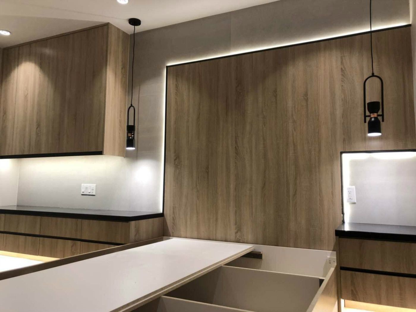 Modern home office renovation in Markham featuring custom wood panel wall design, built-in storage cabinetry, floating desk, and ambient LED strip lighting. The warm wood tones paired with sleek black accents create a functional and stylish workspace that enhances productivity while maintaining a clean, contemporary residential interior.