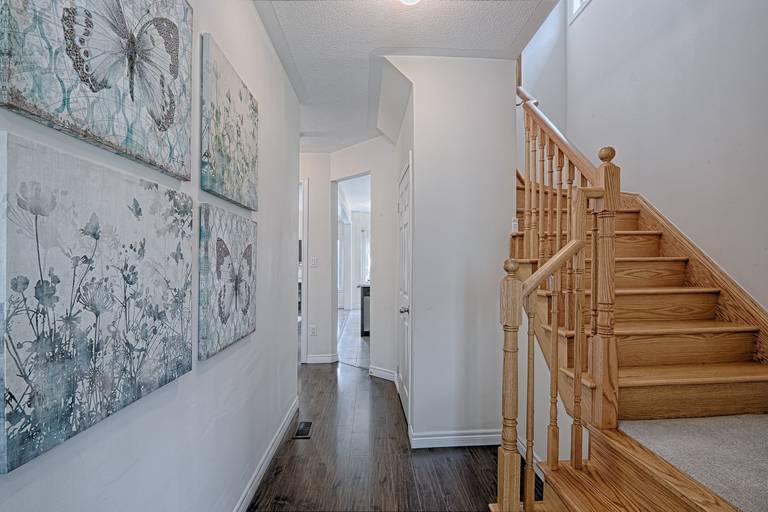 This modern interior renovation highlights a beautifully finished wooden staircase paired with dark hardwood hallway flooring for a warm yet contemporary contrast. The clean white walls, coordinated artwork, and streamlined layout enhance visual continuity throughout the home. Designed to improve flow between levels while maintaining a cohesive aesthetic, this staircase and hallway upgrade reflects the craftsmanship of a trusted Toronto renovation company specializing in full home interior renovations and modern residential design.