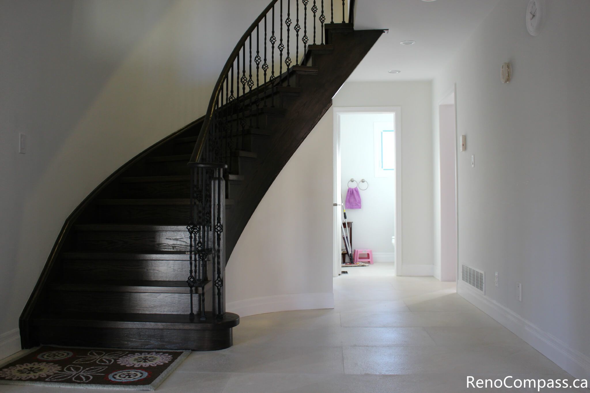 This Mississauga interior renovation features a modern staircase upgrade with dark hardwood steps, custom iron railings, and a bright open entryway design. The clean wall finishes, recessed lighting, and updated flooring enhance both functionality and visual appeal, creating a welcoming and elegant interior space. Completed by a trusted Toronto renovation company, Reno Compass Inc., this project highlights professional craftsmanship and contemporary home renovation design.