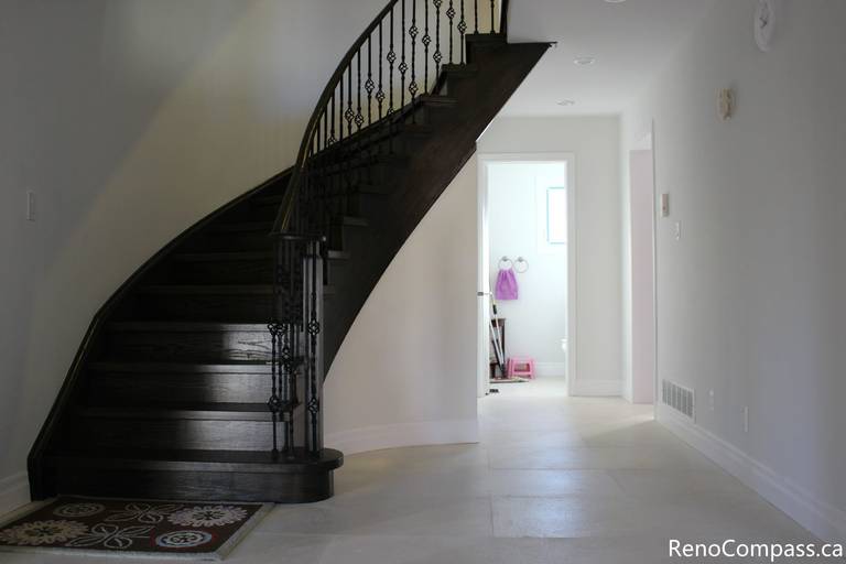 This Mississauga interior renovation features a modern staircase upgrade with dark hardwood steps, custom iron railings, and a bright open entryway design. The clean wall finishes, recessed lighting, and updated flooring enhance both functionality and visual appeal, creating a welcoming and elegant interior space. Completed by a trusted Toronto renovation company, Reno Compass Inc., this project highlights professional craftsmanship and contemporary home renovation design.