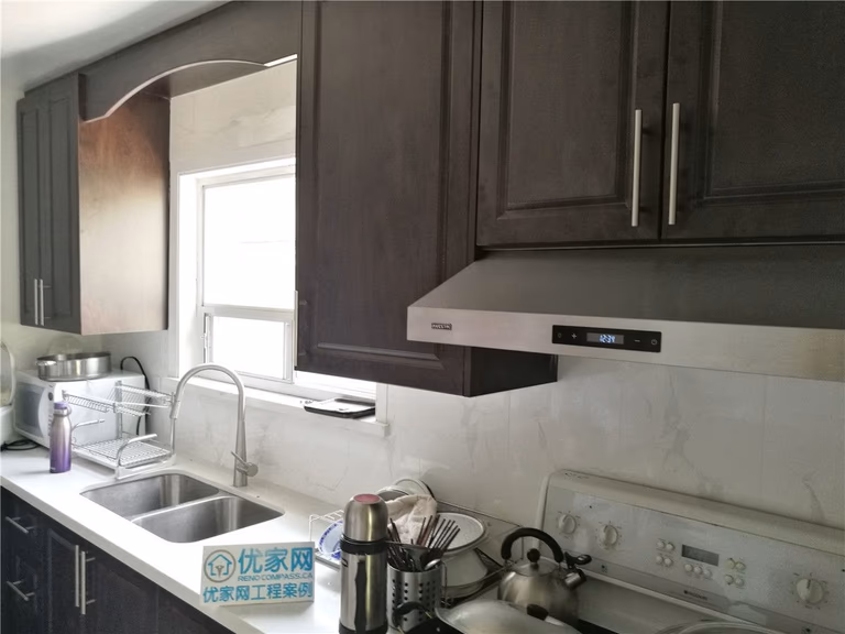 A view of the existing kitchen in Richmond Hill before renovation, showing dark cabinetry, stainless steel appliances, and a compact layout to be transformed by Toronto renovation company Reno Compass Inc.
