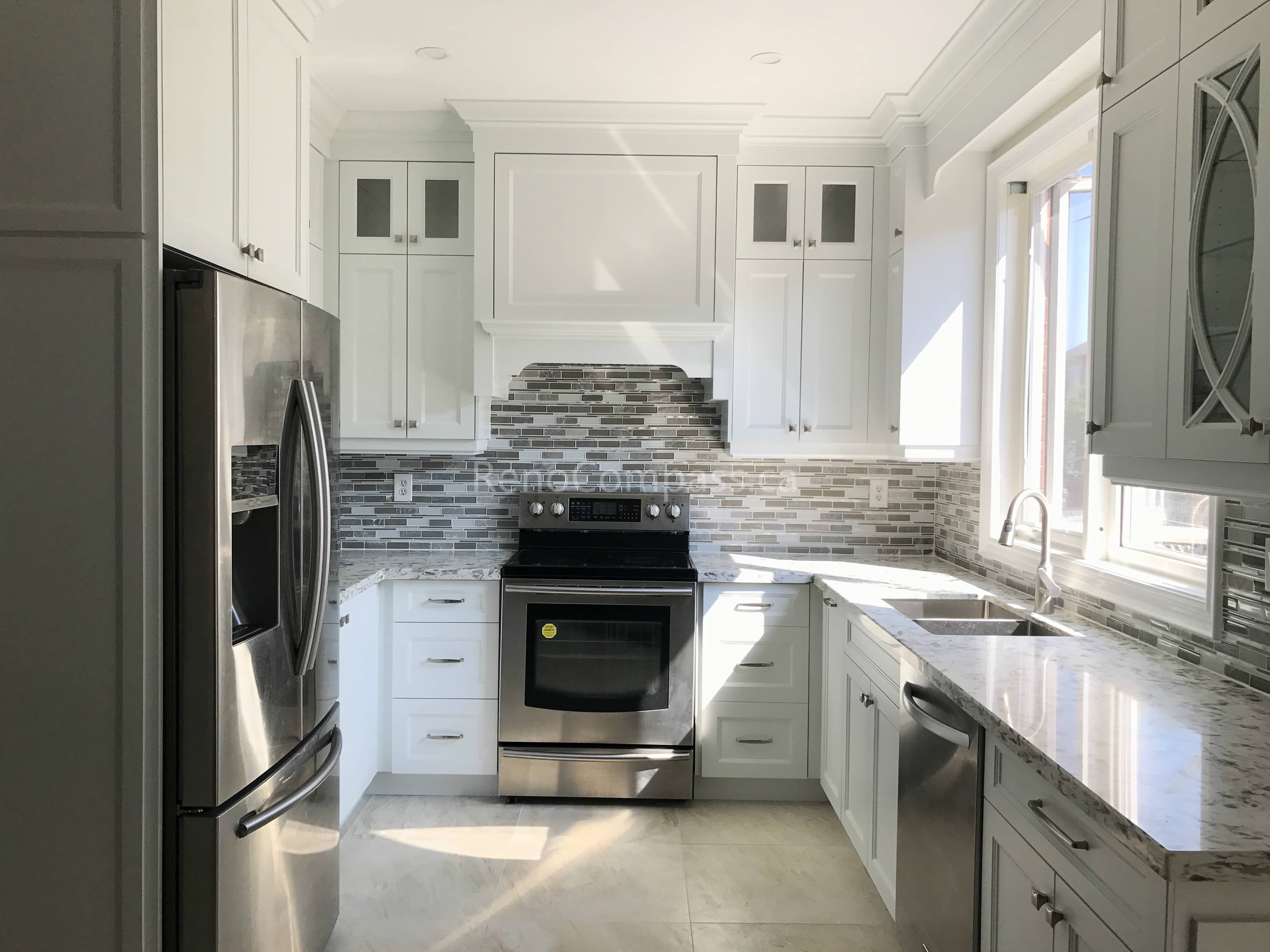 This Markham kitchen renovation features custom white cabinetry, a modern mosaic tile backsplash, and stainless steel appliances. The layout was redesigned to improve workflow and natural light, creating a bright, functional, and timeless cooking space ideal for everyday family use.