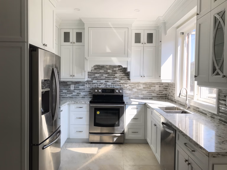 This Markham kitchen renovation features custom white cabinetry, a modern mosaic tile backsplash, and stainless steel appliances. The layout was redesigned to improve workflow and natural light, creating a bright, functional, and timeless cooking space ideal for everyday family use.
