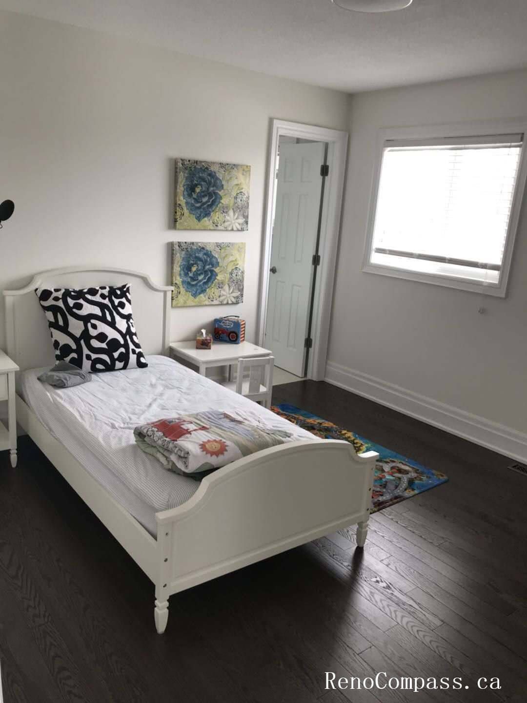 This Markham interior renovation project features a bright and elegantly refreshed bedroom space. The upgrade includes rich dark hardwood flooring, clean white trim work, modern wall finishes, and updated lighting to create a warm and contemporary atmosphere. The minimalist furniture layout enhances natural light flow, while the neutral color palette provides a timeless and functional design. Completed with attention to detail and craftsmanship, this bedroom renovation reflects Reno Compass’ expertise in delivering high-quality interior upgrades in Markham and the Greater Toronto Area.