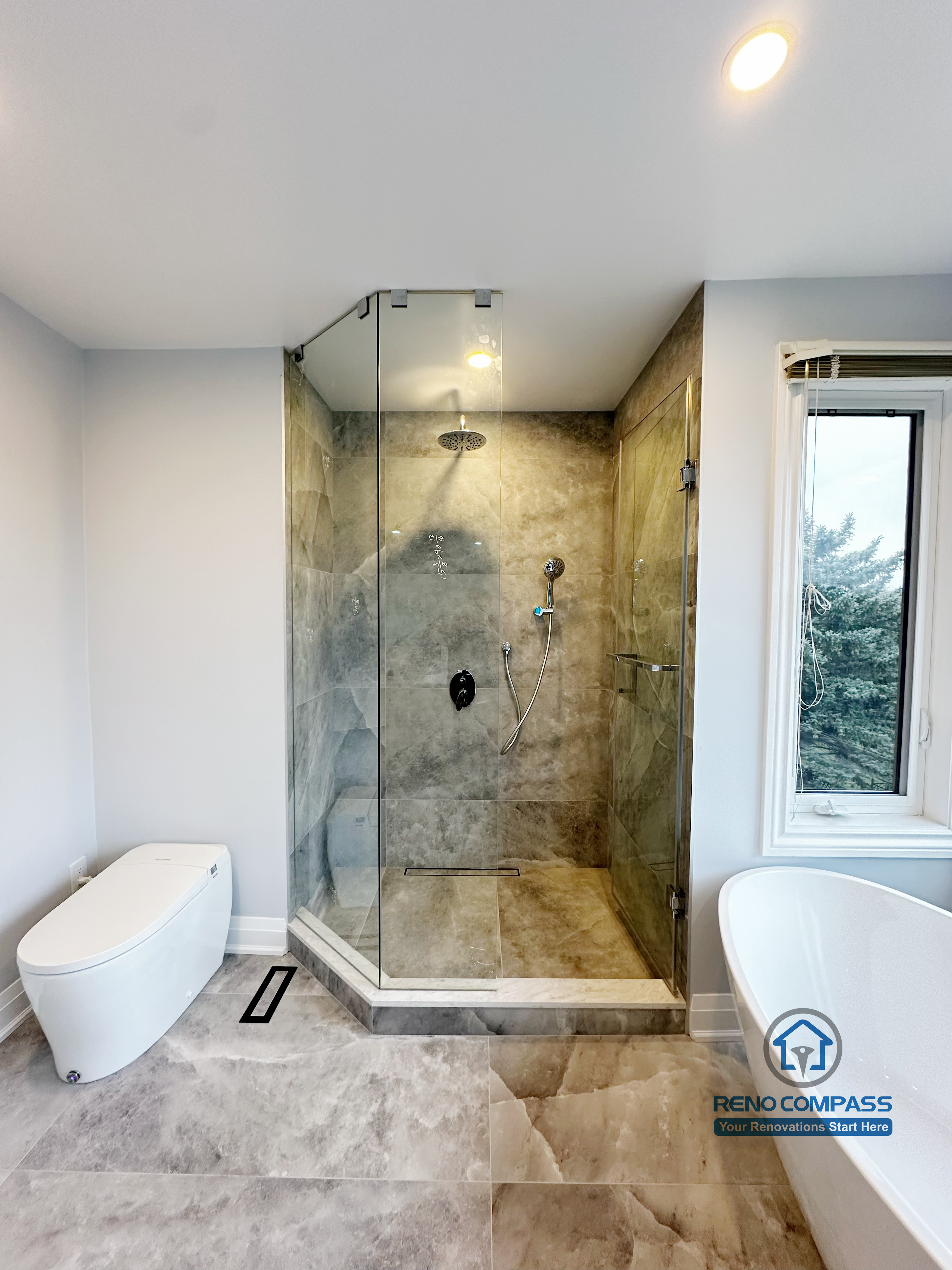 Bathroom renovation in Markham featuring a walk-in glass shower with large-format stone-look tiles, a streamlined toilet, and a clean modern layout. The design prioritizes functionality, durability, and a bright, well-balanced spatial feel.