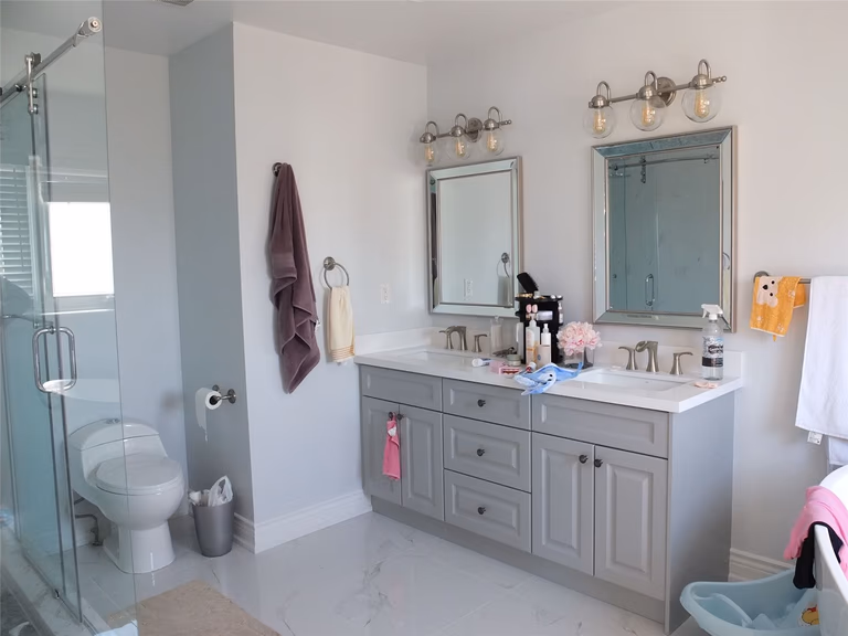 This Richmond Hill bathroom renovation features a clean white vanity with quartz countertop, modern undermount sink, upgraded faucet, and sleek glass shower enclosure. The bright flooring and functional layout enhance daily comfort and property value, showcasing professional craftsmanship by a trusted Toronto renovation company serving Richmond Hill and the GTA.