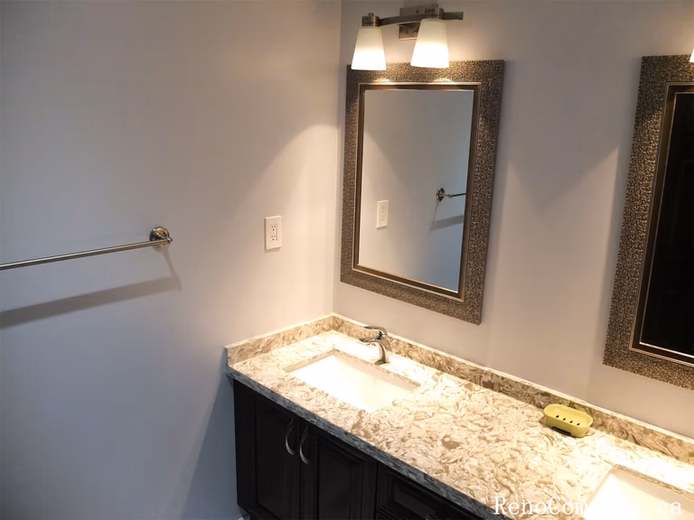 This Richmond Hill interior renovation features a stylish bathroom vanity upgrade with a marble-style quartz countertop, modern undermount sink, and custom cabinetry for improved storage. Elegant wall-mounted lighting and framed mirrors enhance brightness and functionality, creating a clean and contemporary bathroom space. The updated fixtures and finishes provide both durability and timeless appeal for everyday use. Completed by a reliable Toronto renovation company, this bathroom renovation adds comfort, practicality, and long-term value to the home.