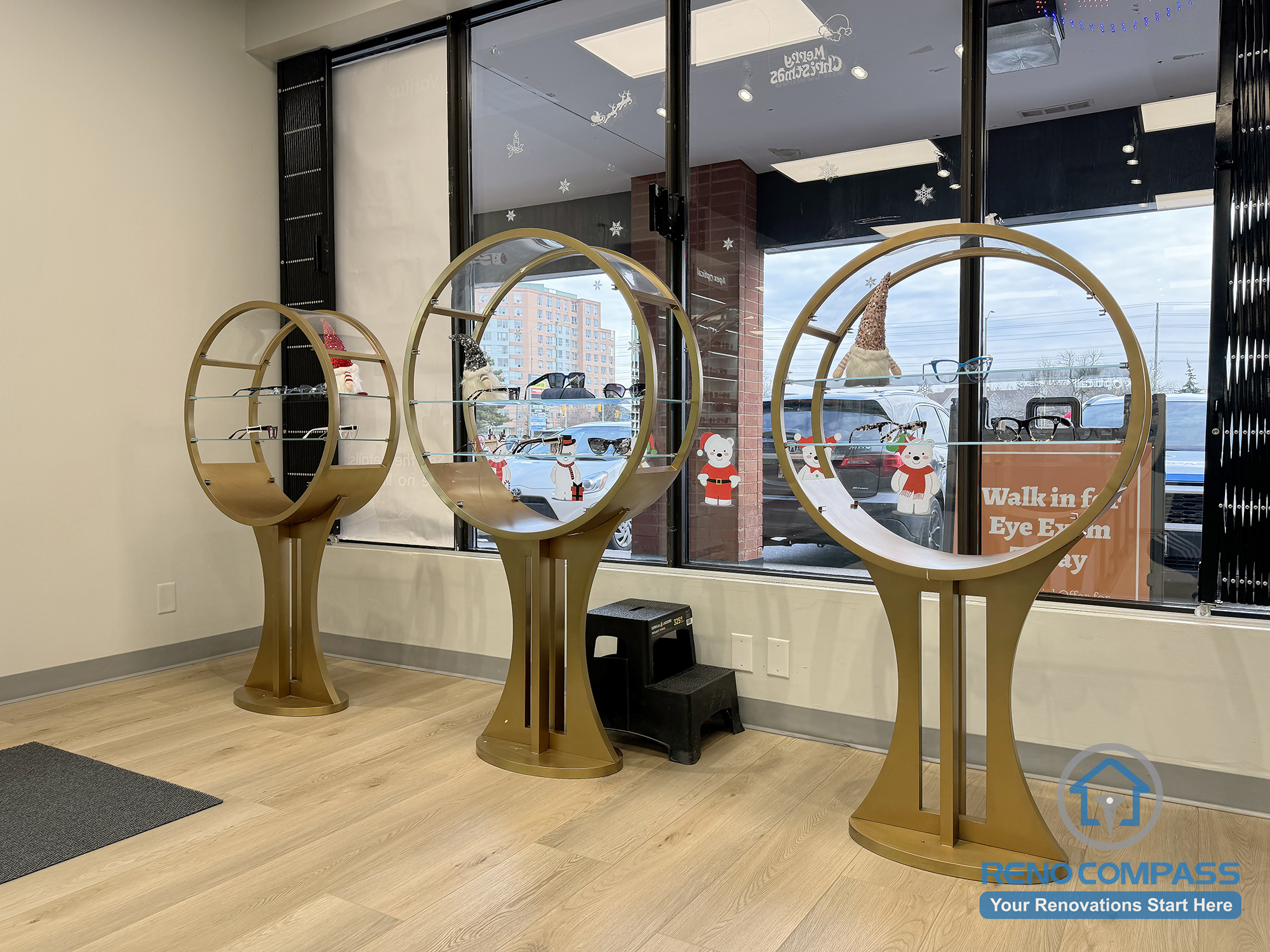 This Mississauga optical store interior renovation features custom circular eyewear display stands, open retail zoning, and floor-to-ceiling storefront windows. The layout emphasizes clear product visibility, smooth customer circulation, and a modern commercial finish designed for eyewear retail environments.