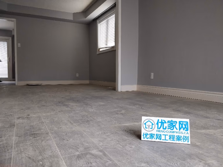 Interior renovation project in Ajax showcasing new grey laminate flooring, freshly painted walls, and updated baseboards. The upgraded living space features a clean, modern finish and improved durability, completed by a professional Toronto renovation company focused on quality residential upgrades.
