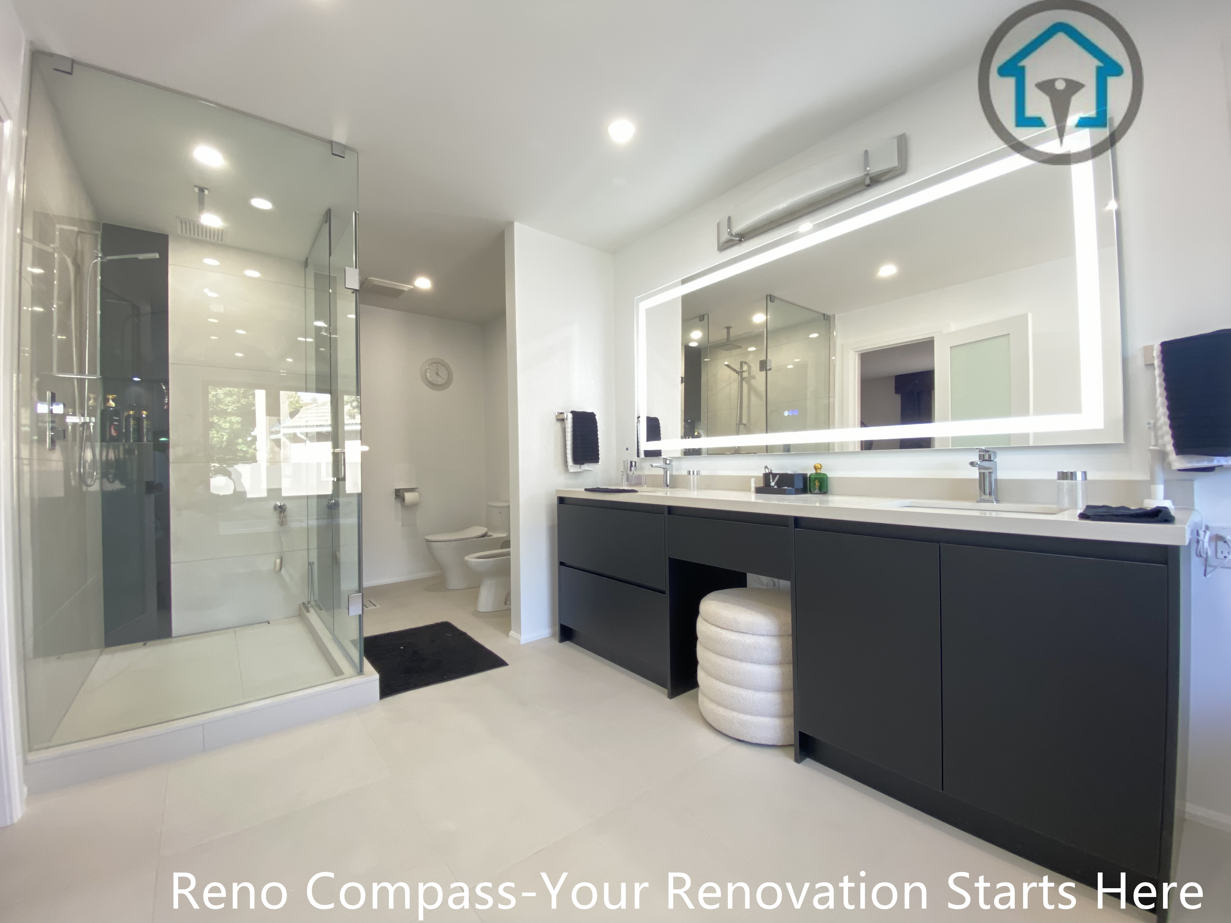 Wide-angle view of a modern bathroom renovation in Brampton featuring a frameless glass shower enclosure, custom double vanity with matte black cabinetry, oversized LED mirror, and clean minimalist finishes. The layout emphasizes openness, functionality, and everyday comfort, completed by a professional Toronto renovation company.