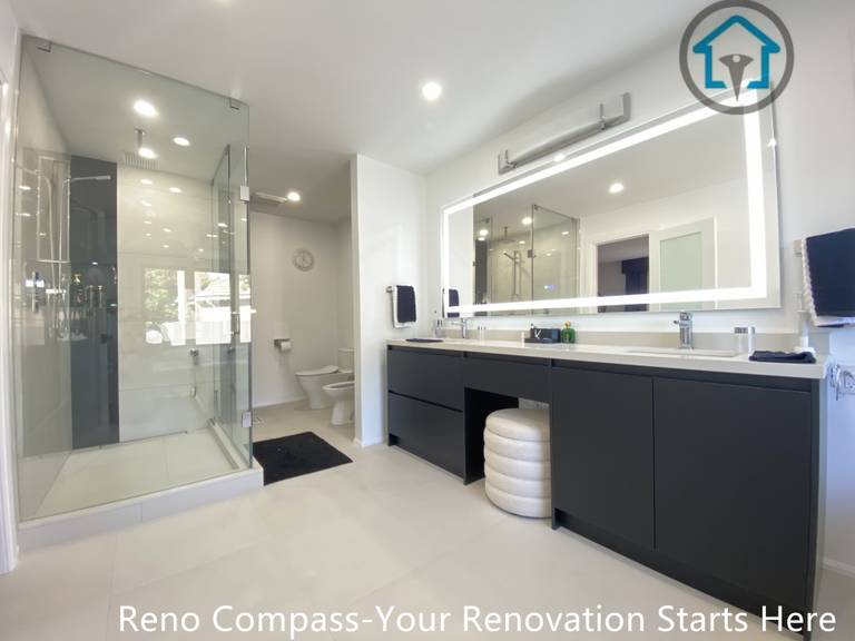 Wide-angle view of a modern bathroom renovation in Brampton featuring a frameless glass shower enclosure, custom double vanity with matte black cabinetry, oversized LED mirror, and clean minimalist finishes. The layout emphasizes openness, functionality, and everyday comfort, completed by a professional Toronto renovation company.