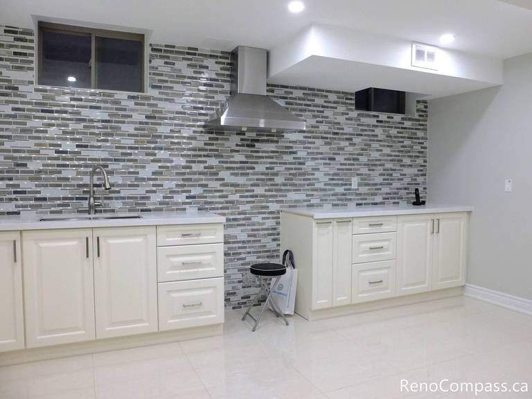 Modern basement kitchen installation in Markham featuring white shaker-style cabinetry, quartz countertop, stainless steel range hood, and full-height mosaic tile backsplash. The sleek layout and bright finishes enhance both functionality and visual appeal, making the basement a fully usable secondary living space. Completed by a professional Toronto renovation company, this project reflects attention to detail and high-quality craftsmanship.