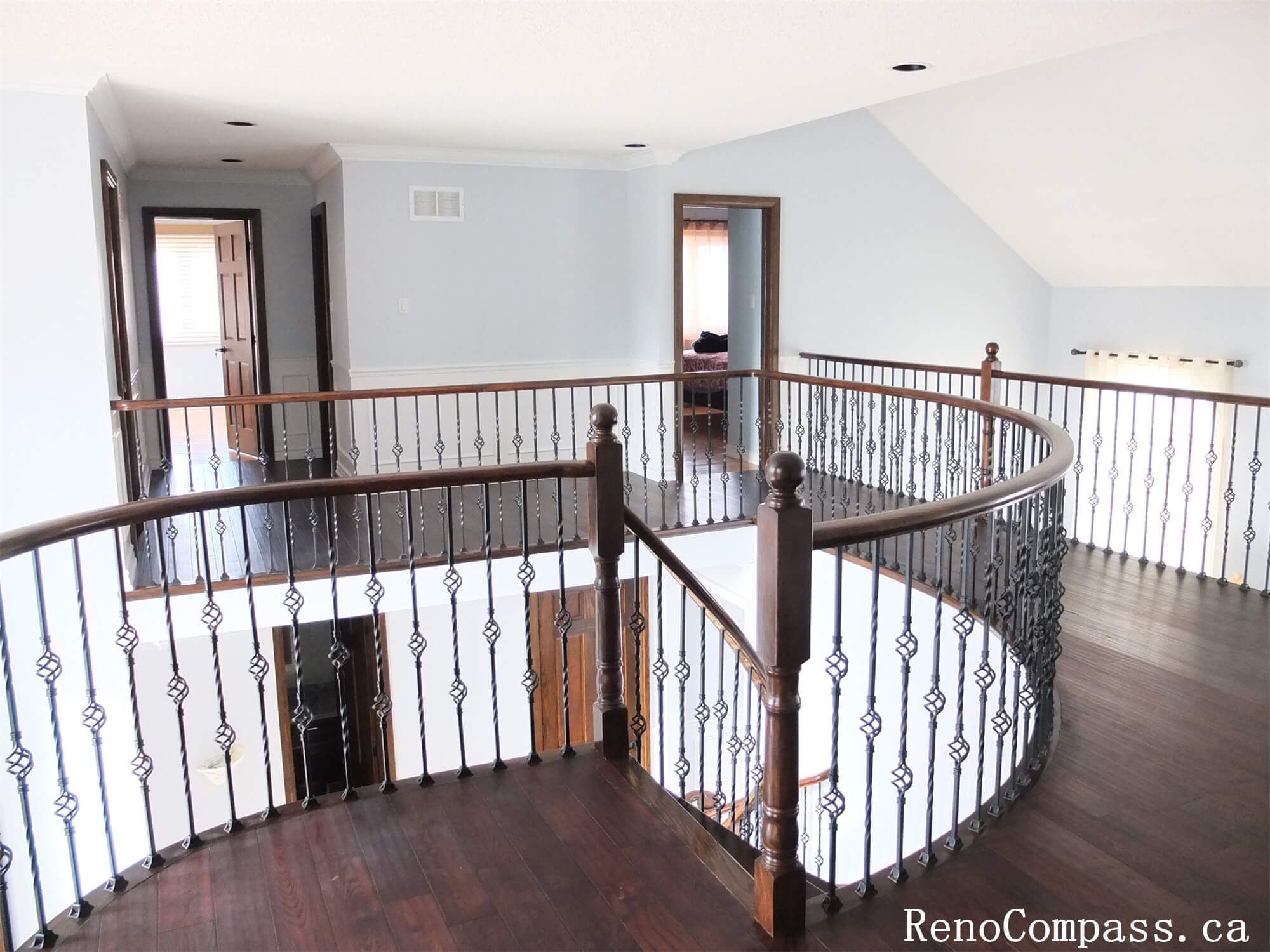 This Richmond Hill interior renovation features a spacious second-floor staircase landing with dark wood flooring and custom wrought iron railings. The updated staircase area enhances the home's architectural elegance while providing a bright and open transition between floors.