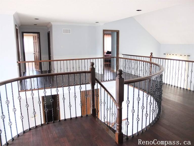 This Richmond Hill interior renovation features a spacious second-floor staircase landing with dark wood flooring and custom wrought iron railings. The updated staircase area enhances the home's architectural elegance while providing a bright and open transition between floors.
