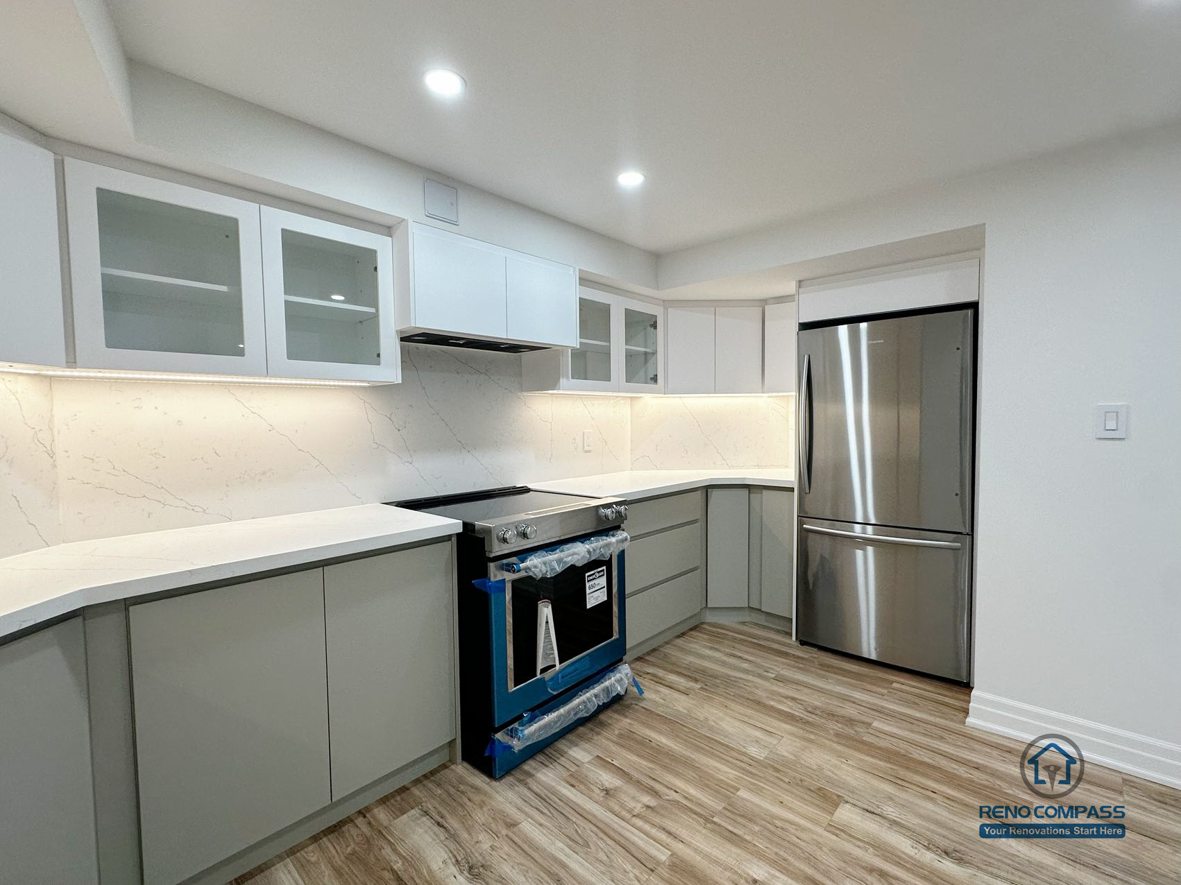 This image showcases a side-angle view of a completed basement kitchen renovation in Pickering, highlighting the integration of appliances within a clean and efficient layout. Custom cabinetry, built-in appliances, and continuous countertop surfaces support smooth workflow and everyday usability. Under-cabinet lighting enhances visibility across the workspace, while neutral finishes and consistent flooring help the kitchen blend seamlessly into the surrounding basement living area. The overall design prioritizes functionality, durability, and long-term use within a multi-purpose lower-level environment.
Location: Pickering · Toronto Contractor: Reno Compass
