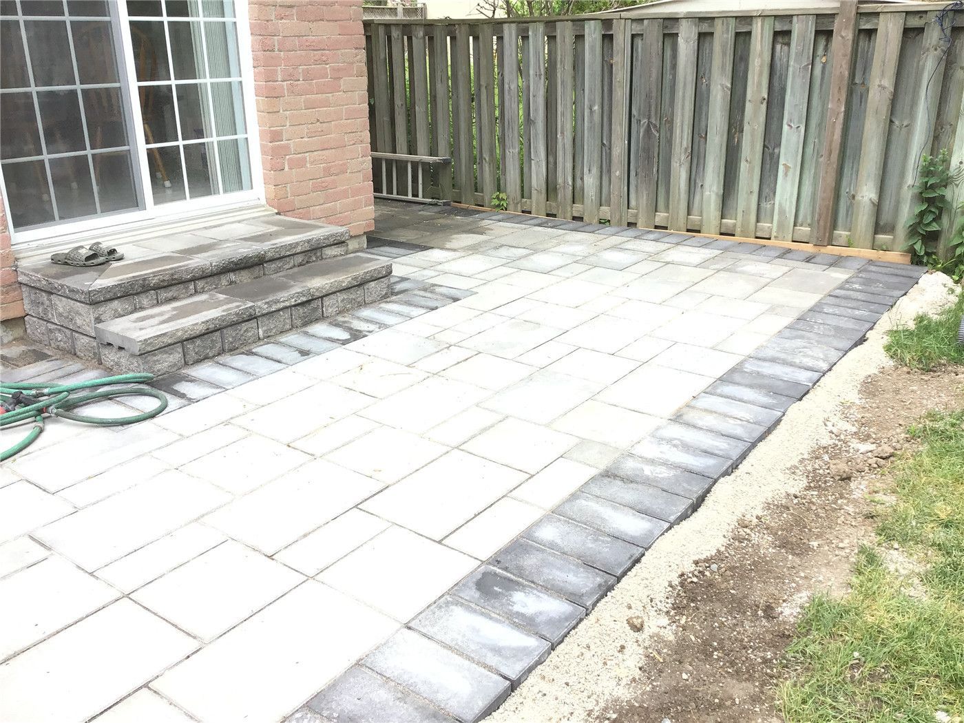 This Oakville interlocking project features a spacious backyard patio built with large-format grey pavers and clean border detailing. The design includes solid step construction leading to the entrance, creating a functional and visually balanced outdoor space. Ideal for relaxing or entertaining, this low-maintenance patio enhances both usability and property value.