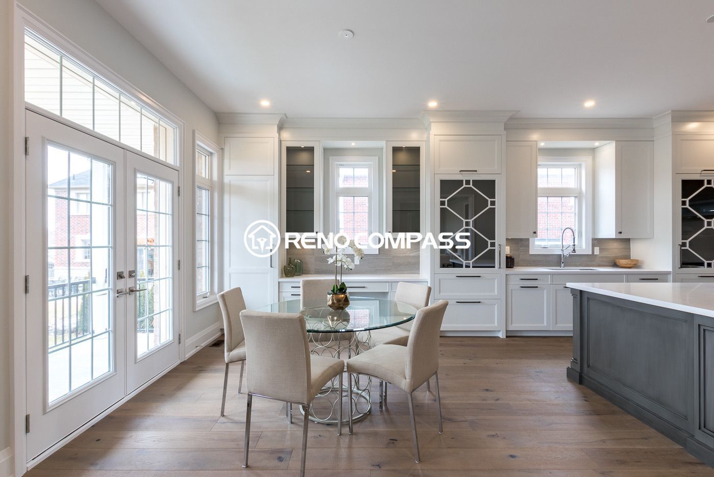 This Newmarket kitchen renovation features a bright open-concept layout connecting the kitchen and dining area. Custom white cabinetry, engineered wood flooring, and large windows create a spacious and elegant interior filled with natural light. Completed by a trusted Toronto renovation company, Reno Compass Inc., the design combines modern aesthetics with functional living space for everyday family use.